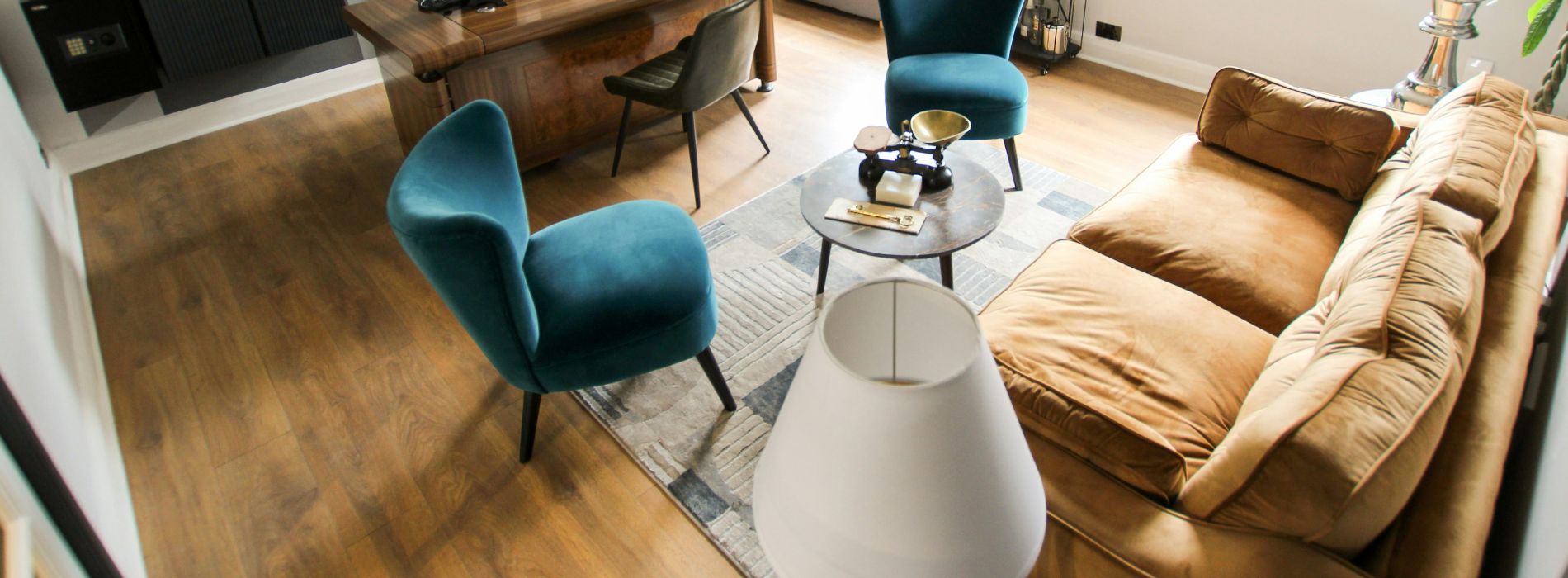 Chic, contemporary living area featuring plush teal chairs, a velvety golden sofa, a rustic coffee table, and smooth sanded wooden floors by professionals in Cheam, SM3.