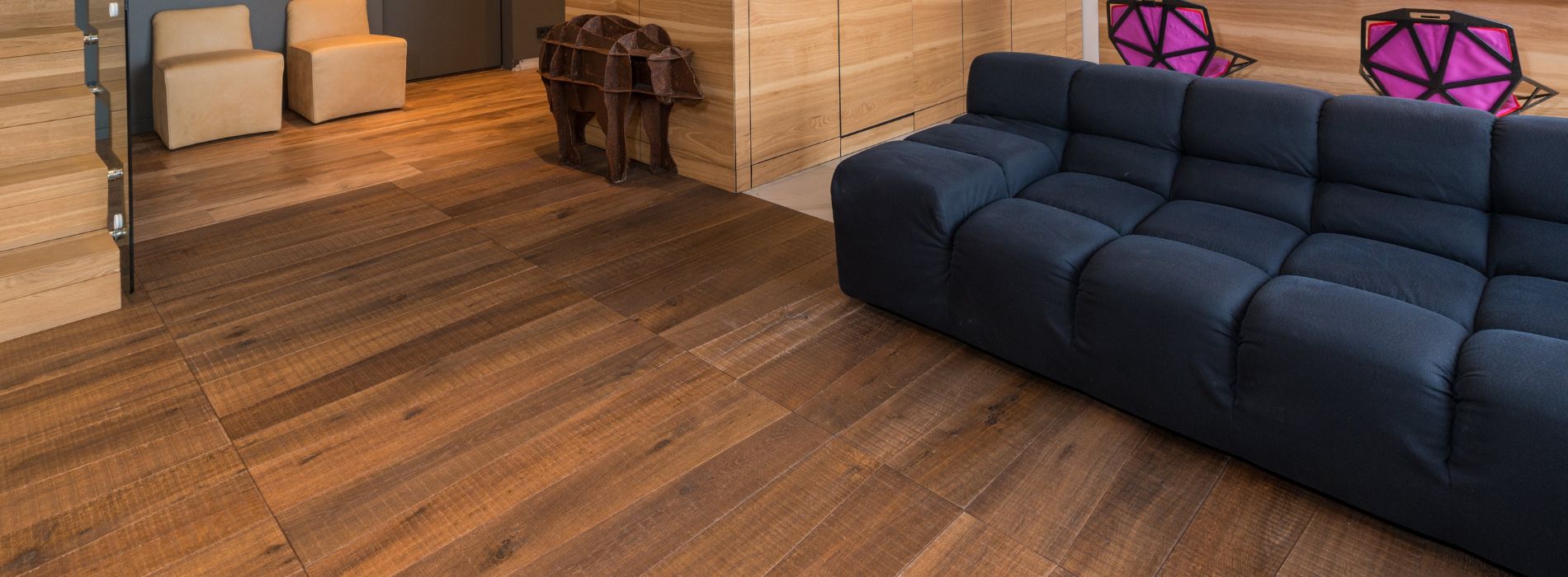 <br />
Contemporary living room with a plush navy sofa, wooden elephant sculpture, modern cabinetry, and beautifully sanded rich hardwood floors in South Wimbledon, SW19.