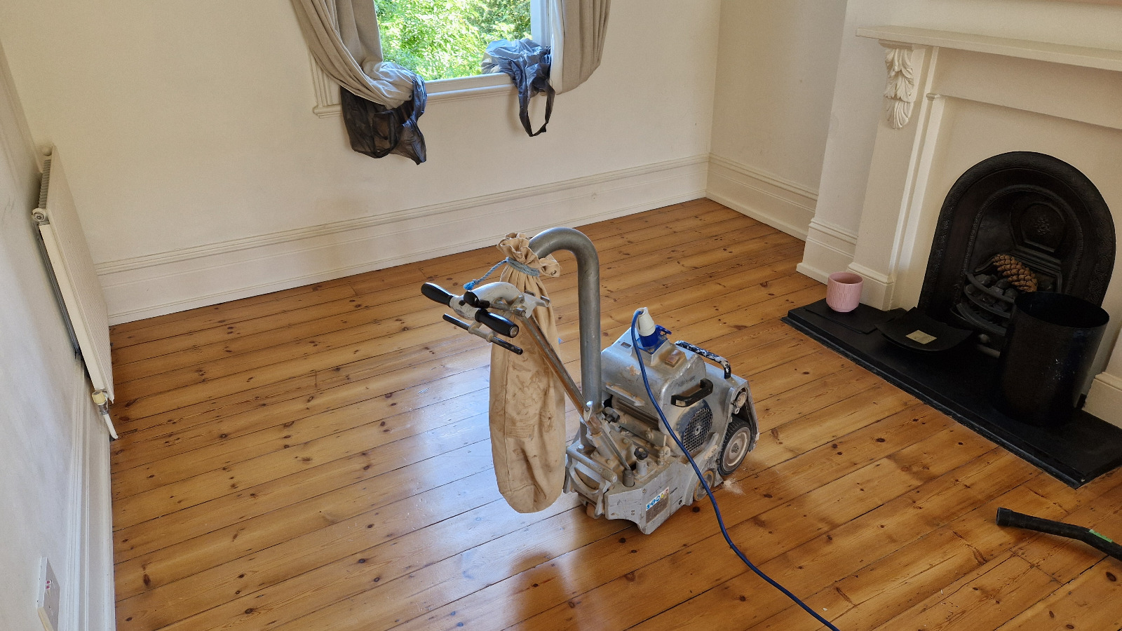 A professional from "Sanding Wood Floors" is using a Bona Belt (AMO110001.3) sander on a floor in Bricket Wood, UK. The sander features a 2.2 kW motor, 1-phase power, 200x750 mm or 250x750 mm belt size, drum width of 200 & 250 mm, and a total weight of 74 kg.