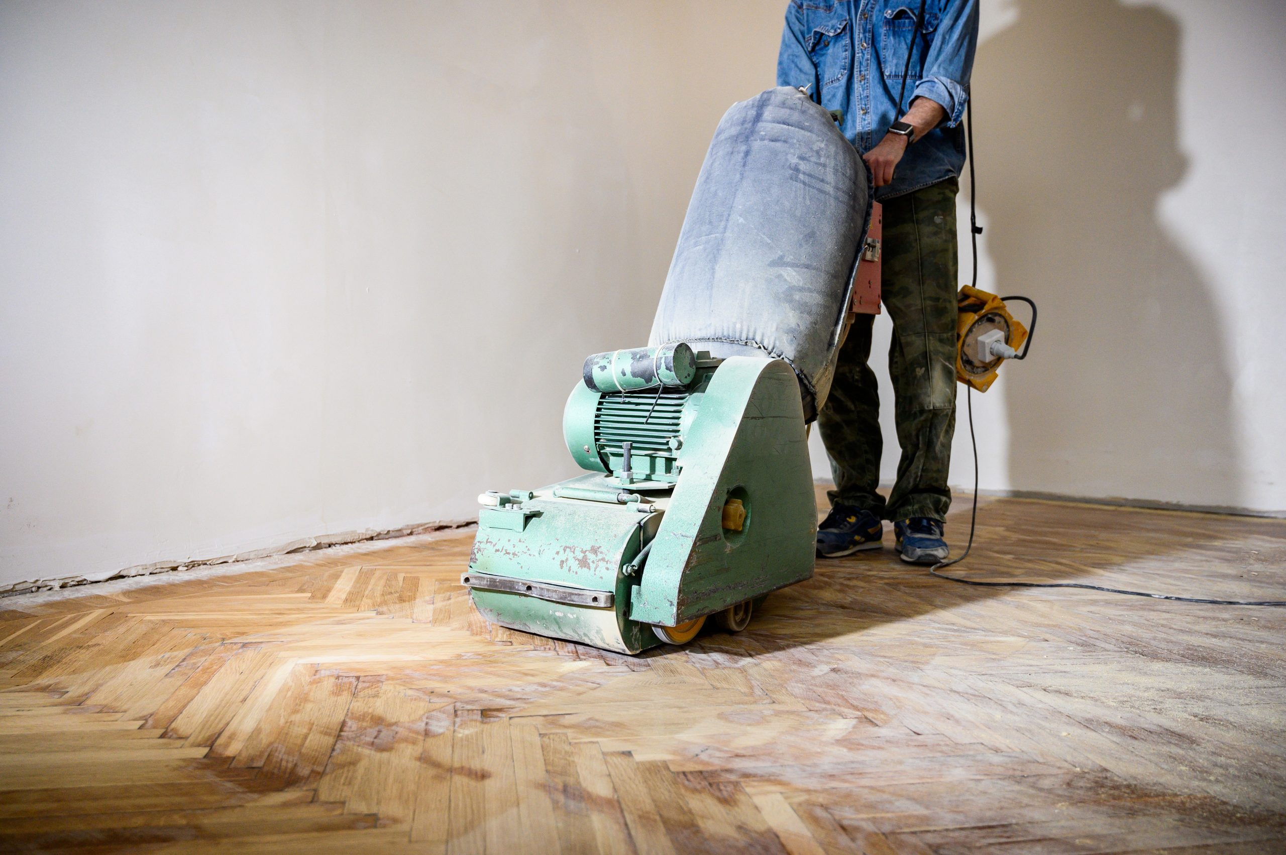A professional from "Sanding Wood Floors" uses a Lagler HUMMEL&reg; floor sanding machine in Felden, UK. The HUMMEL&reg; features a 2.2 kW single-phase AC motor, 230 V, 50 Hz, 200 mm drum width, 2400 rpm drum speed, and 200 x 750 mm sanding belt. The machine weighs 79 kg with low dust emissions and adjustable pressure.