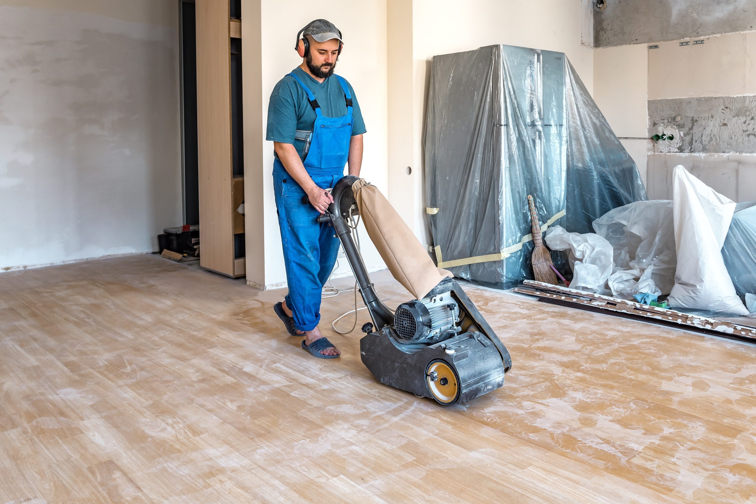 A "Sanding Wood Floors" professional operates a Frank Cobra Belt Sander on a floor in Felden, UK. The machine features a 2500W motor, 78 kg weight, and 2100 rpm sanding speed. It uses a 200 x 750 mm endless belt and offers 99.99% dust extraction through an integrated DCS connection, ensuring powerful and dust-free sanding.