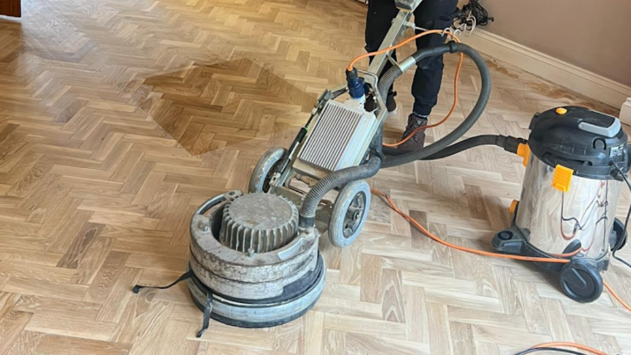 Rotary polishing machine smoothing an oak herringbone parquet floor after expert Parquet Repairs.