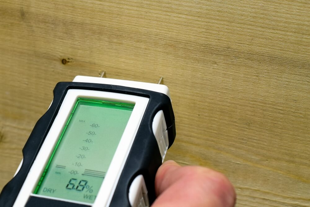Pin-type moisture meter reading 6.8% on oak mosaic fingers parquet before applying varnish to wood floors.