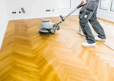 Maintenance Tips: technician buffing freshly sanded oak herringbone parquet wood floor with a rotary machine for an even, durable shine.