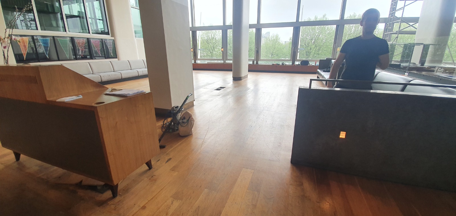 Office Floor Sanding in a reception lounge on an oak plank solid hardwood floor, showing worn traffic lanes and equipment staged for sanding and refinishing.