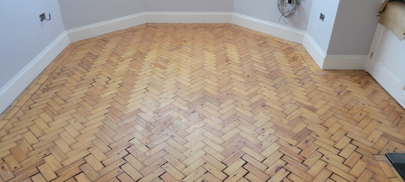 Parquet Repairs — worn pine herringbone parquet floor before restoration, with visible gaps and dull finish ready for sanding, gap filling and sealing.