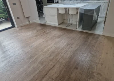 How to Fix Dull Traffic Lanes on an oak engineered plank floor shown with worn, greyed traffic lanes in an open-plan kitchen before restoration.